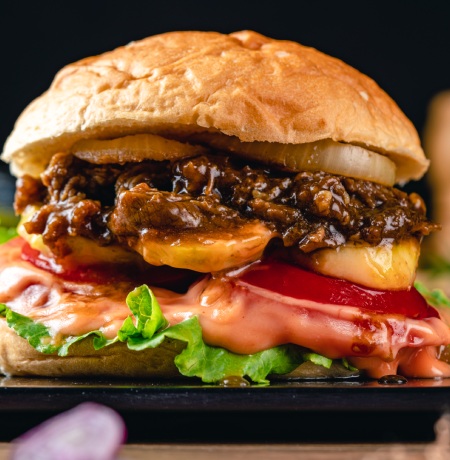 A burger with melted cheese and mayo.