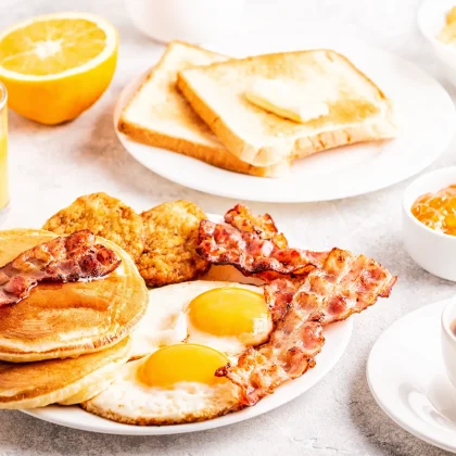 A healthy american breakfast with eggs and bacon with pancakes and orange juice.